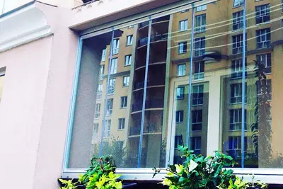 Скління балкона з квітами, вид на новобудову
