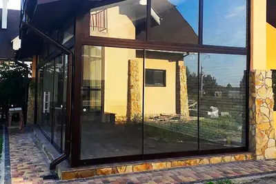 Панорамне скління кутової тераси з жовтим фасадом