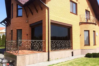 Скління тераси цегляного будинку з кованим огородженням
