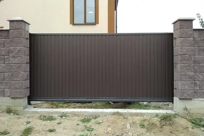 Відкатні ворота між цегляними стовпами перед будинком