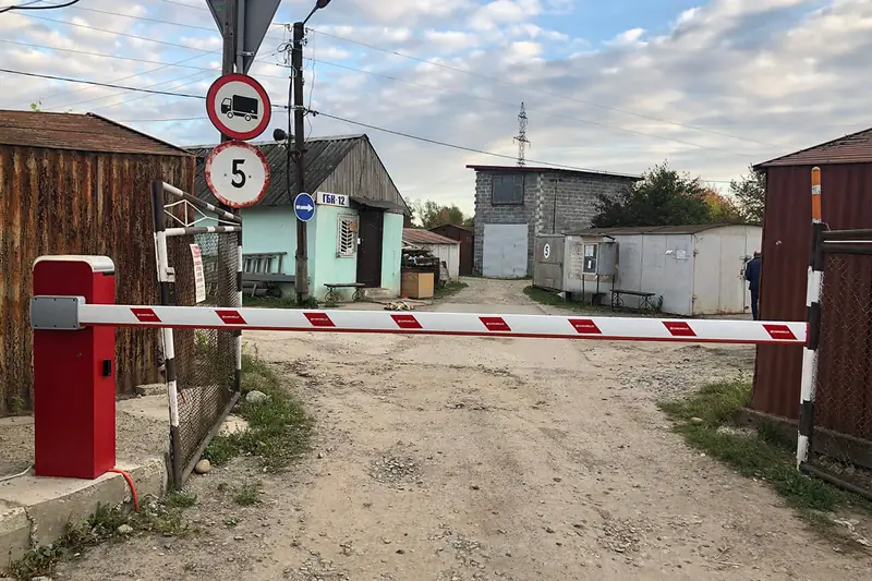 Шлагбаум із піднятою стрілою на в’їзді до бази, поруч знак обмеження швидкості