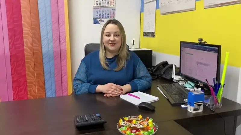 Менеджерка за робочим столом у шоурумі Алюм-Сервіс, поруч зразки ролет